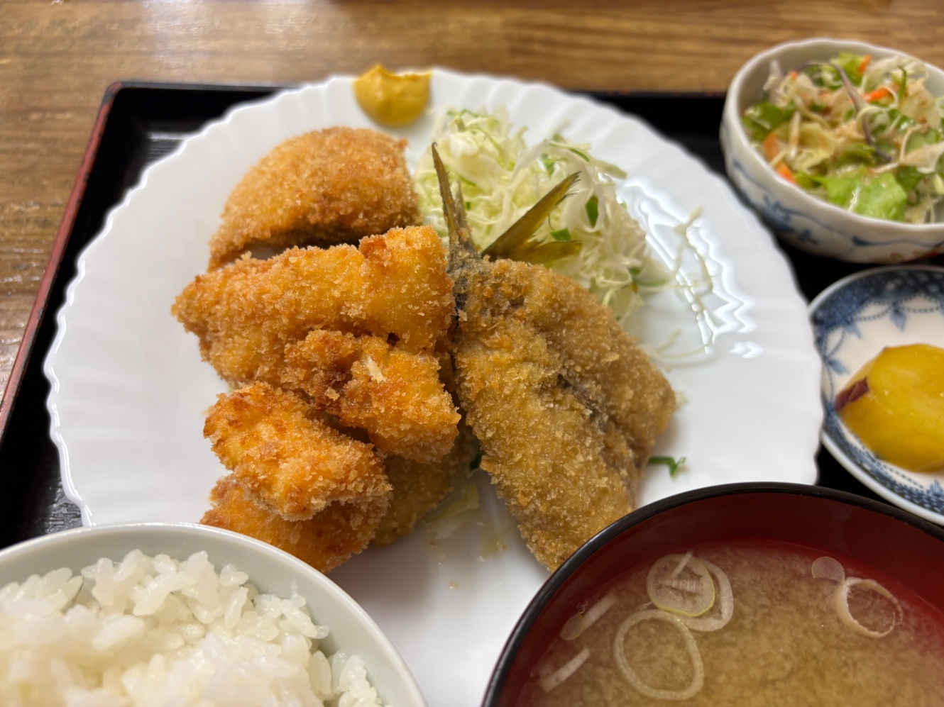 フライ定食のフライの盛り合わせが乗った皿　あじ、いかなど　皿の端にからし、キャベツの千切りも添えてある