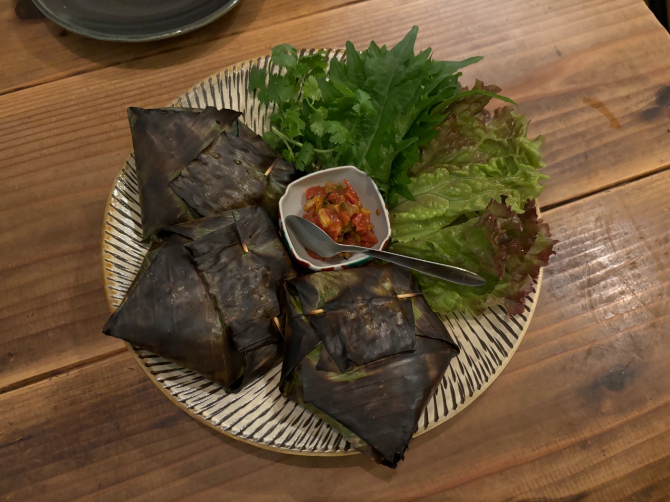 バナナの葉で包んで蒸し焼きにした牛つくねとそえられた薬味