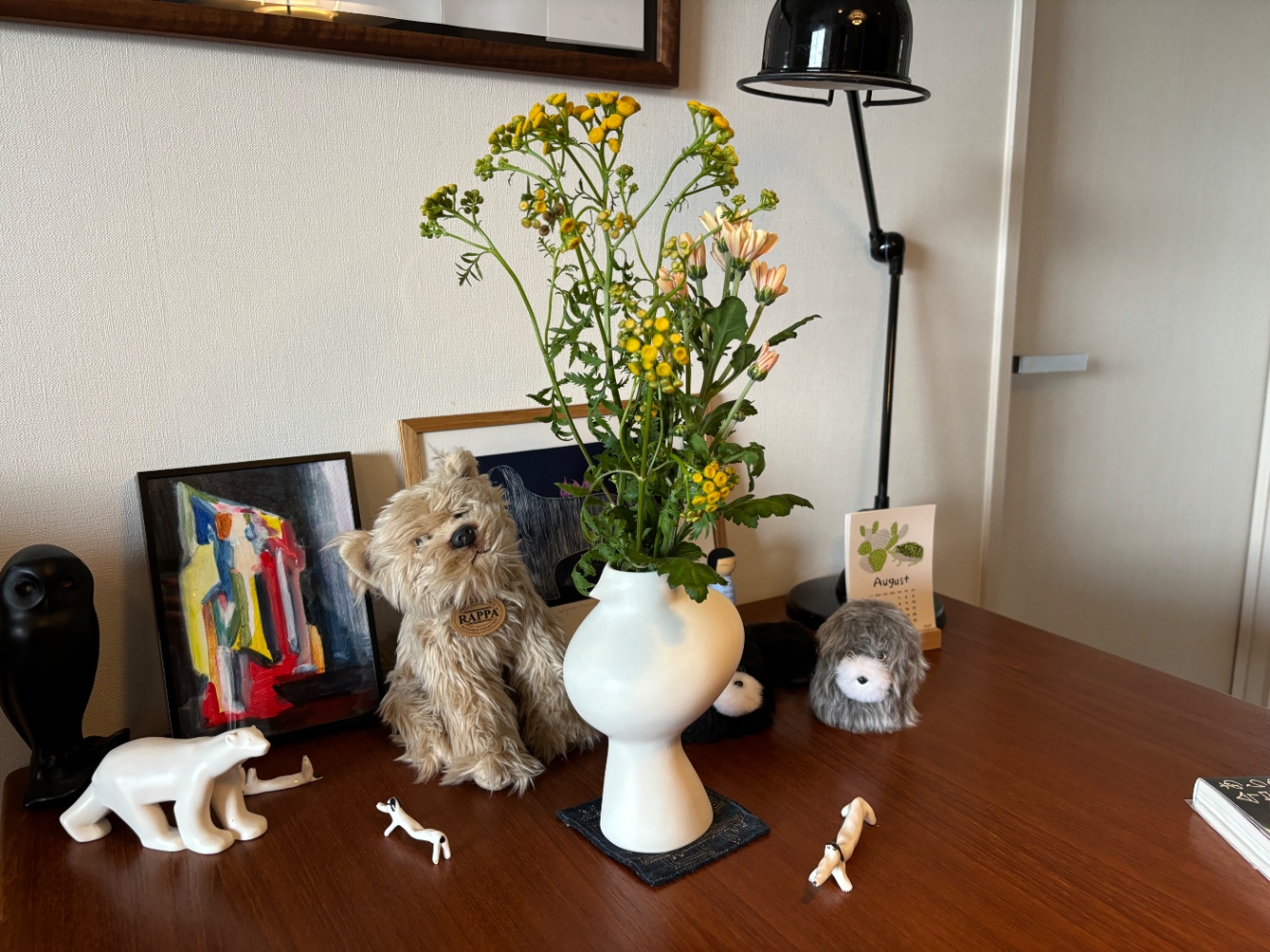 白い鳥のかたちの花瓶に花がいけられている周囲に犬のかたちの箸置き、犬のぬいぐるみ等が置かれている