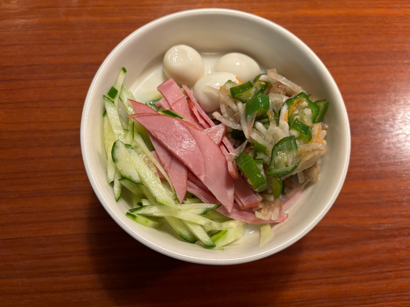 豆腐麺の上にうずらのたまご、オクラと大根の細切り、きゅうり・ハムの細切りが乗っている