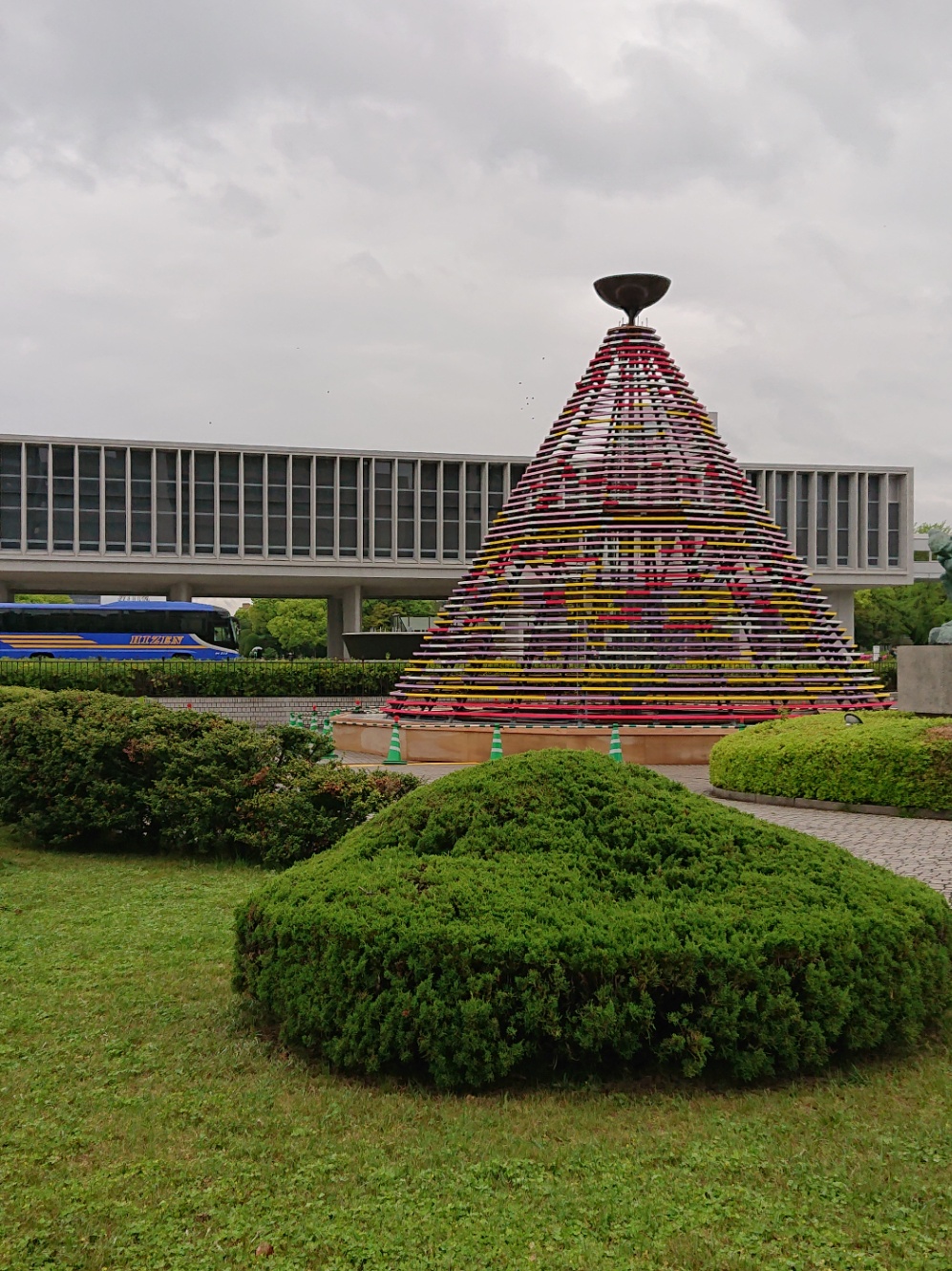 広島平和記念公園内の噴水の側に、フラワーフェスティバルの花の塔がまだ花の無い状態で設置されている。背後には平和記念資料館の建物が見える。