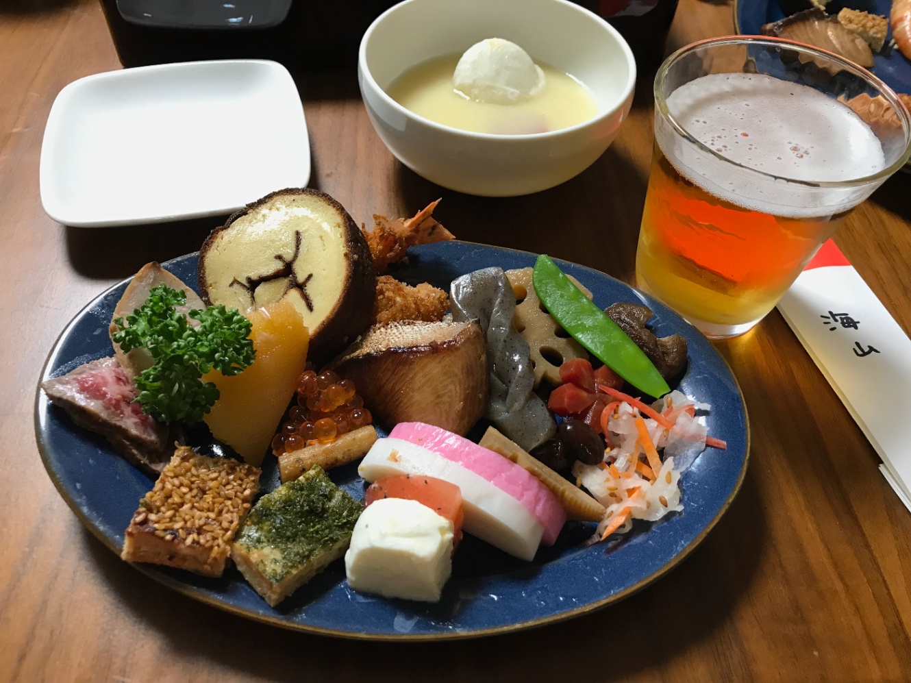 お皿に盛り付けられたお節料理　右側にコップに入ったビール　写真上部にお雑煮