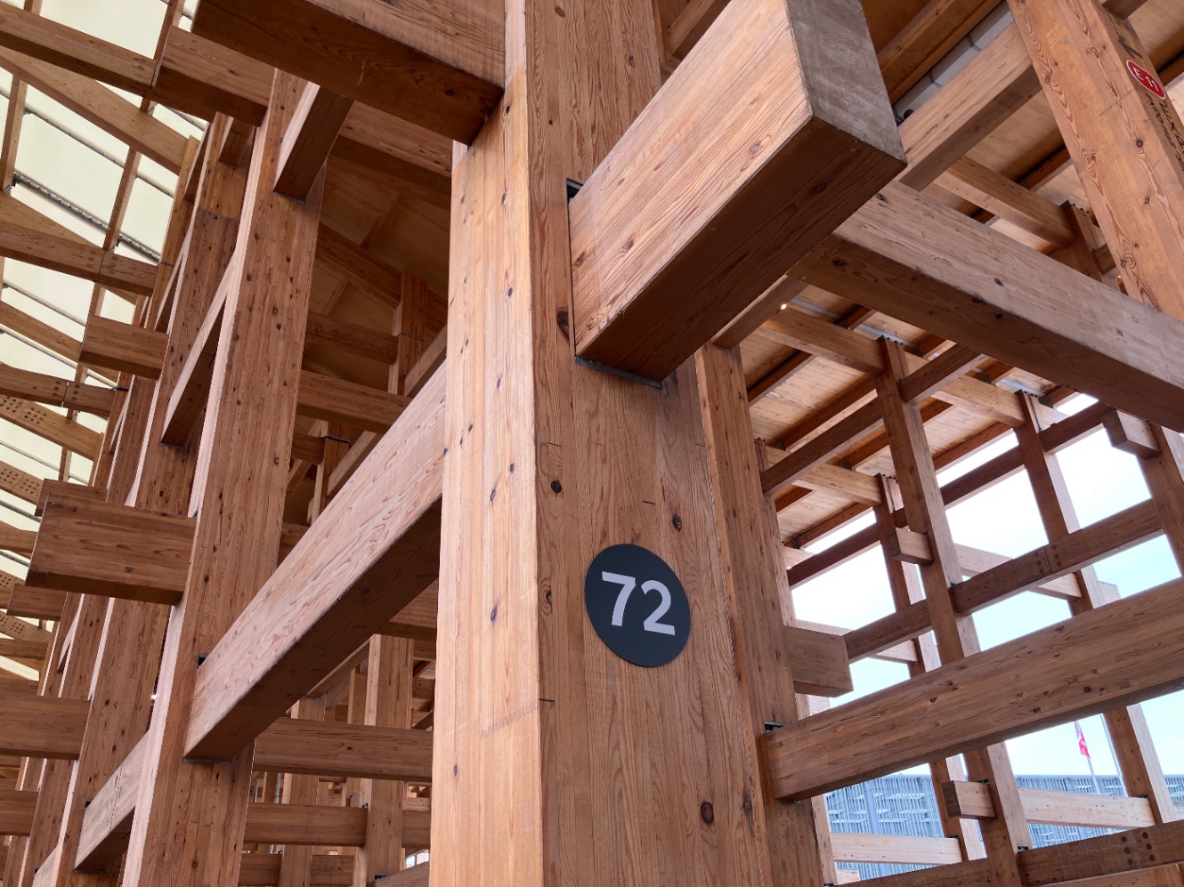 大屋根リングを下から撮った写真。木が入り組んでいる。柱に72の数字