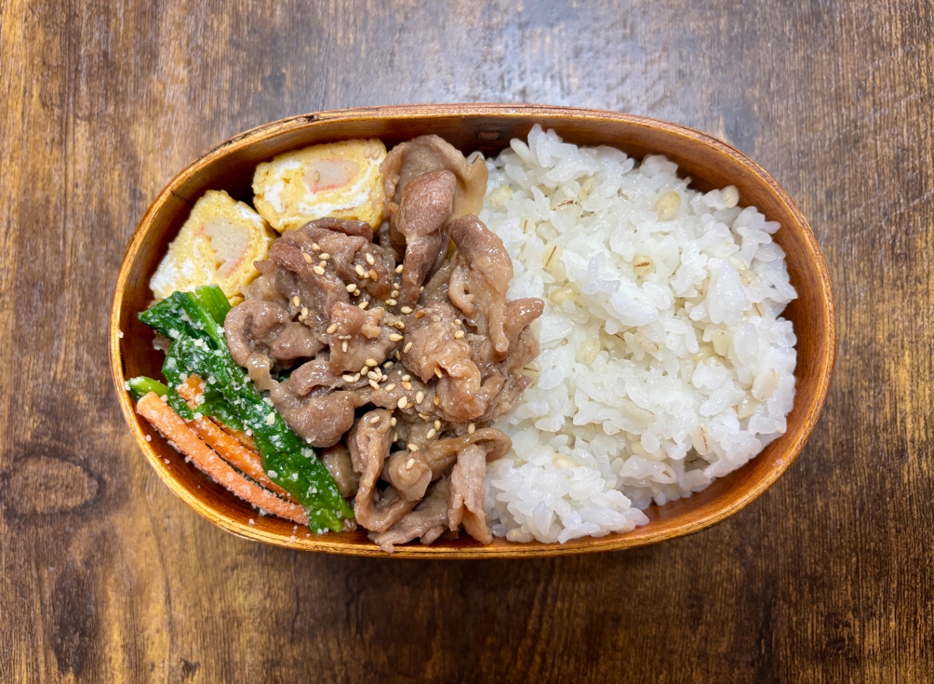 豚こまの焼き肉風、カニカマの卵焼き、ほうれん草とにんじんのチーズ和えと白ごはんの入った弁当