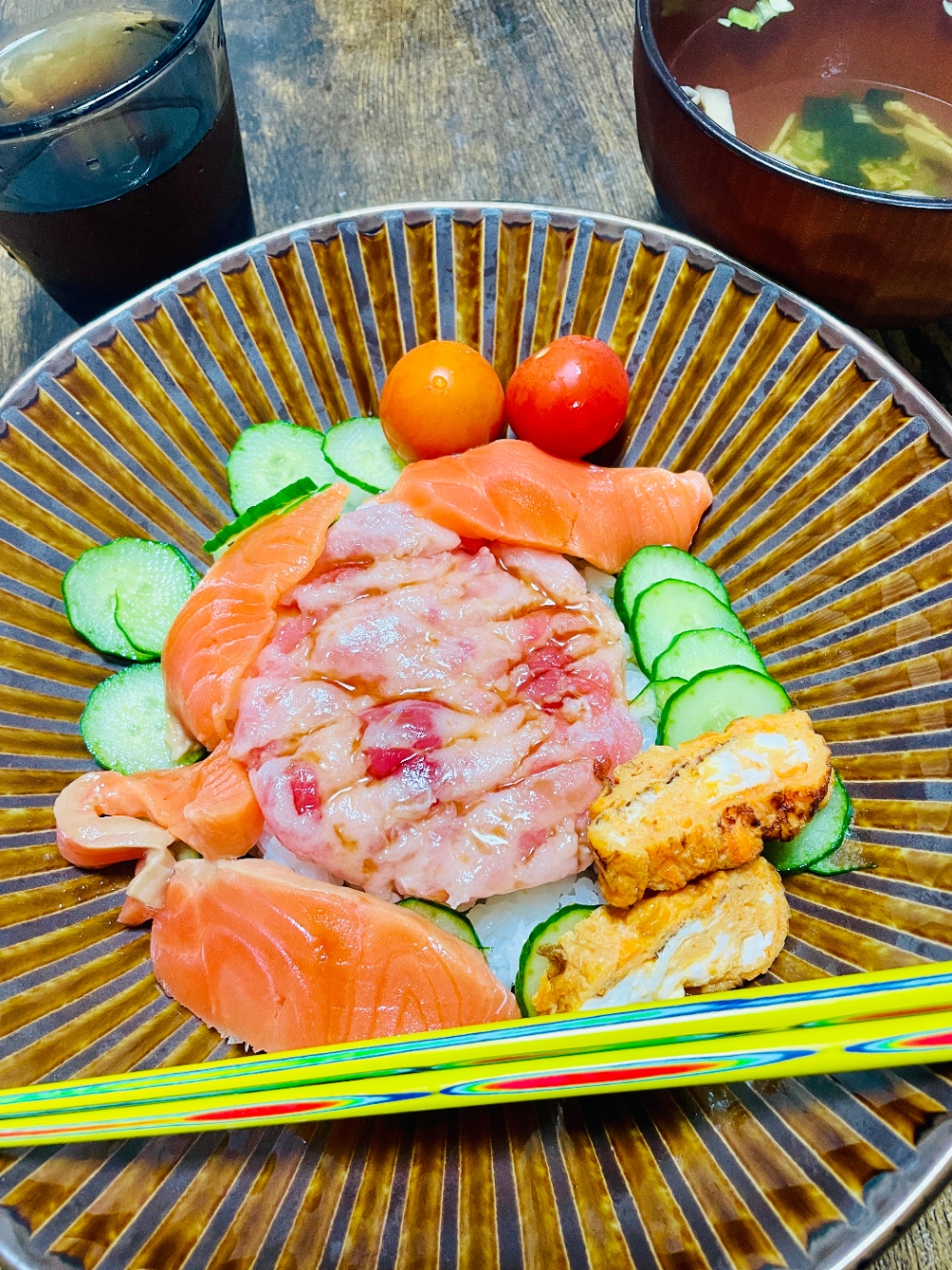 まぐろたたき、サーモン刺、卵焼き、きゅうり、ミニトマト乗っけた丼。奥にインスタントの吸い物。