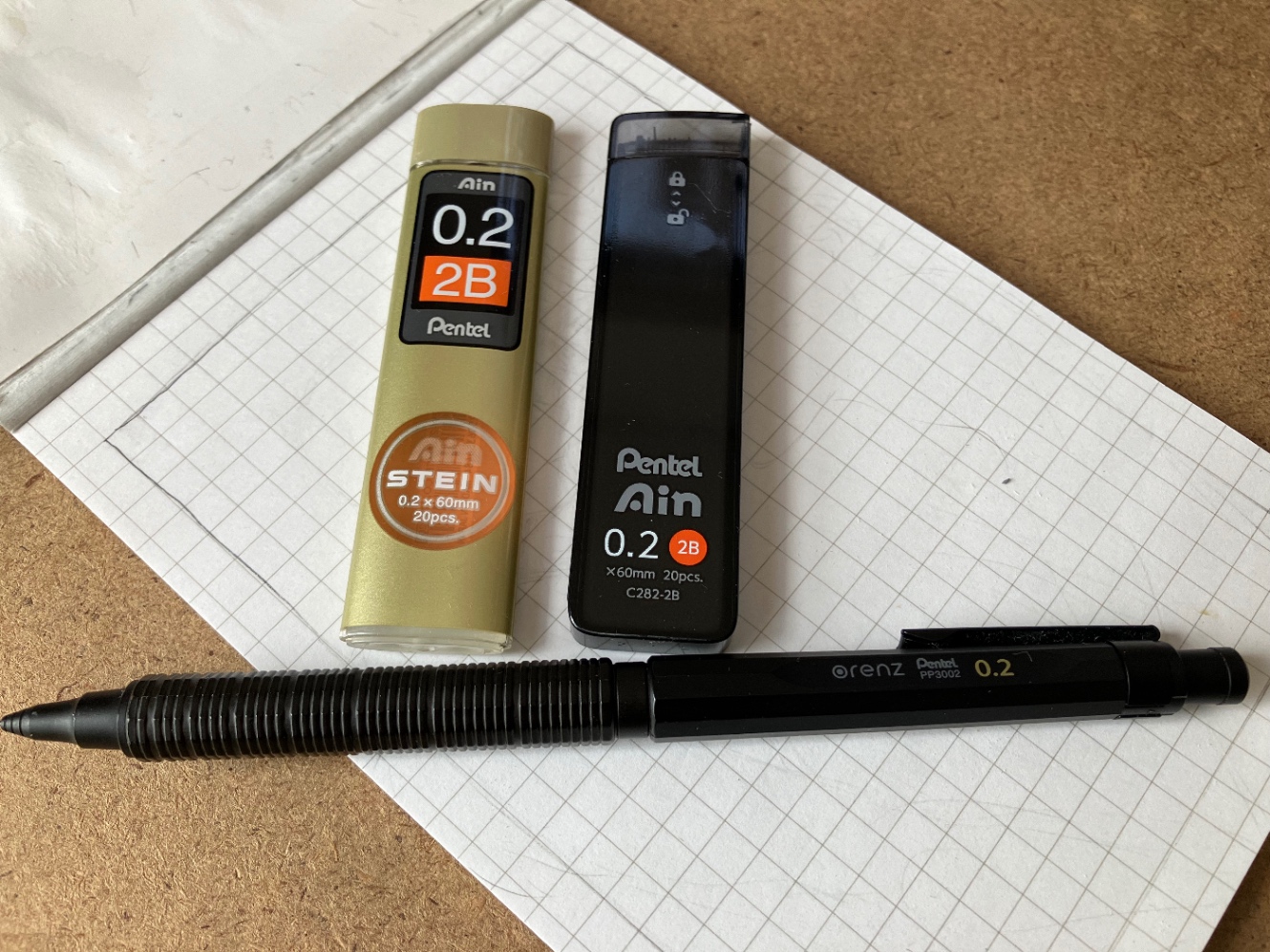 ラフ用の画材、ぺんてるの替芯AinSTEIN0.2mm2Bと、新型のぺんてるAin0.2mm2B、オレンズネロ0.2、A6メモパッドが写っている写真