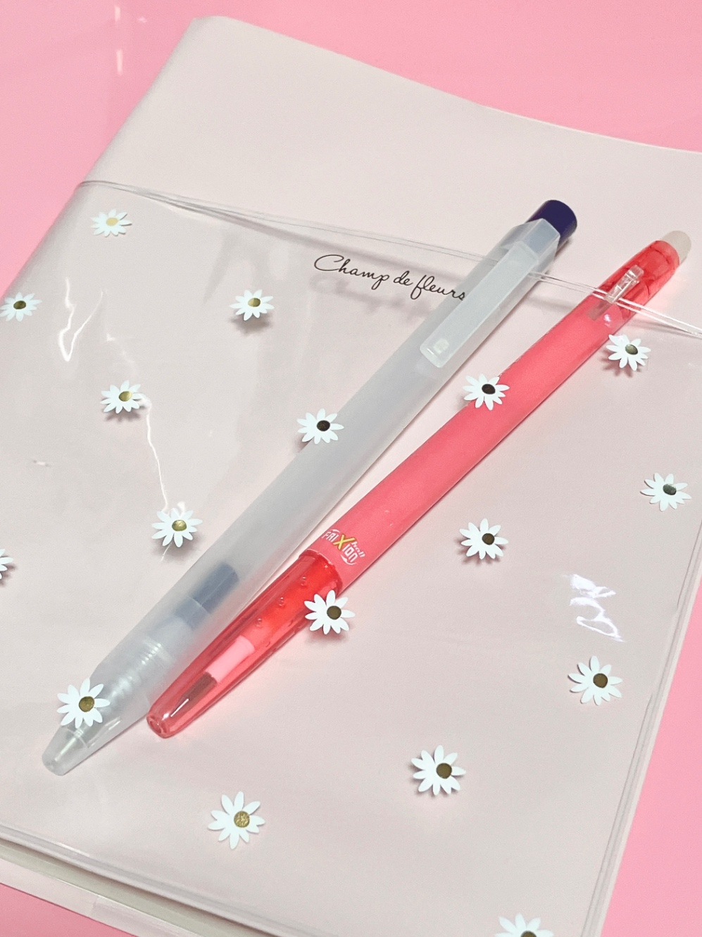 ピンク色の手帳カバー。透明に白の花柄のポケットがついている。