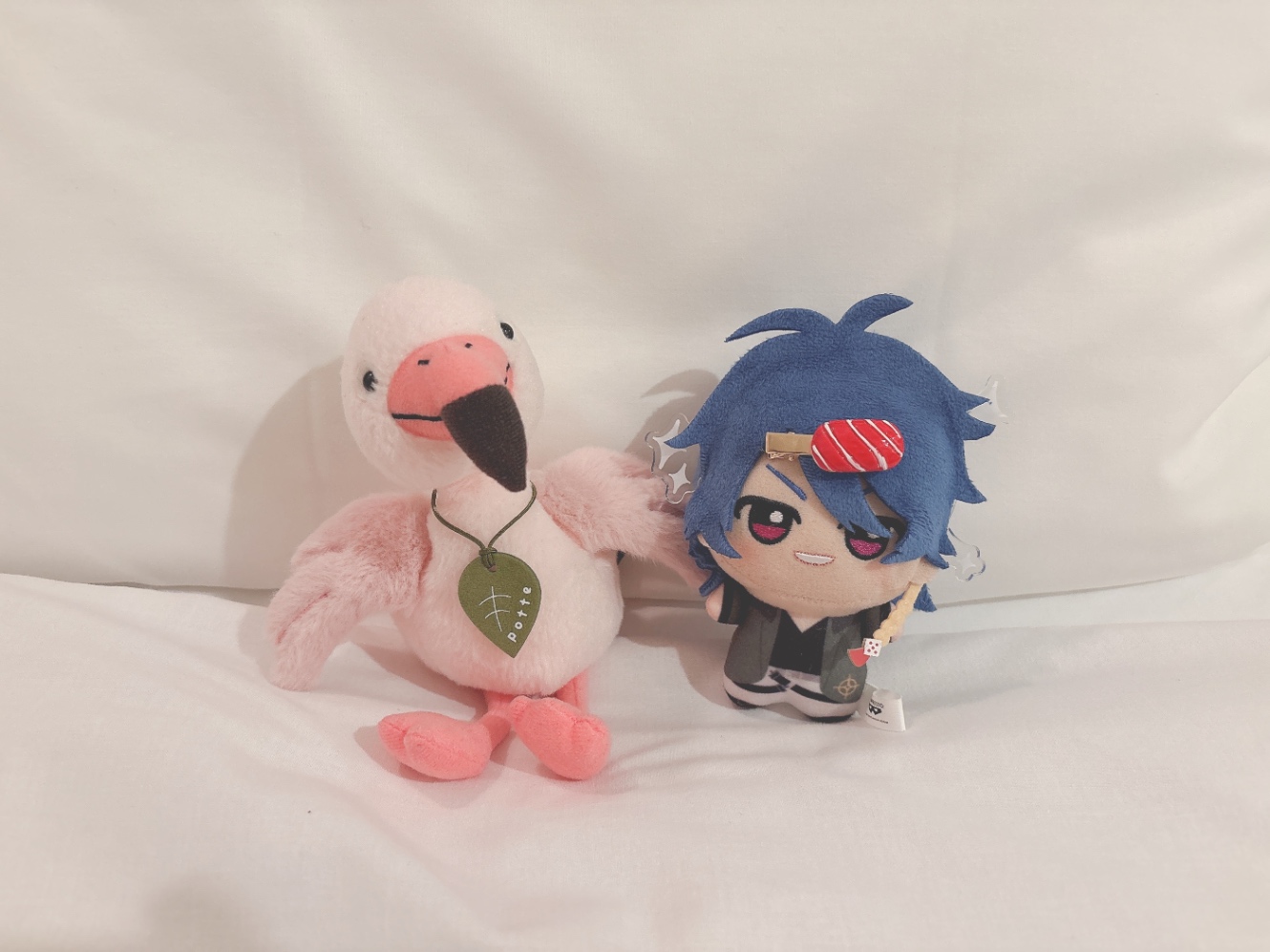 ホテルのベッドにフラミンゴのぬいぐるみと帝統くんのぬいを並べた写真