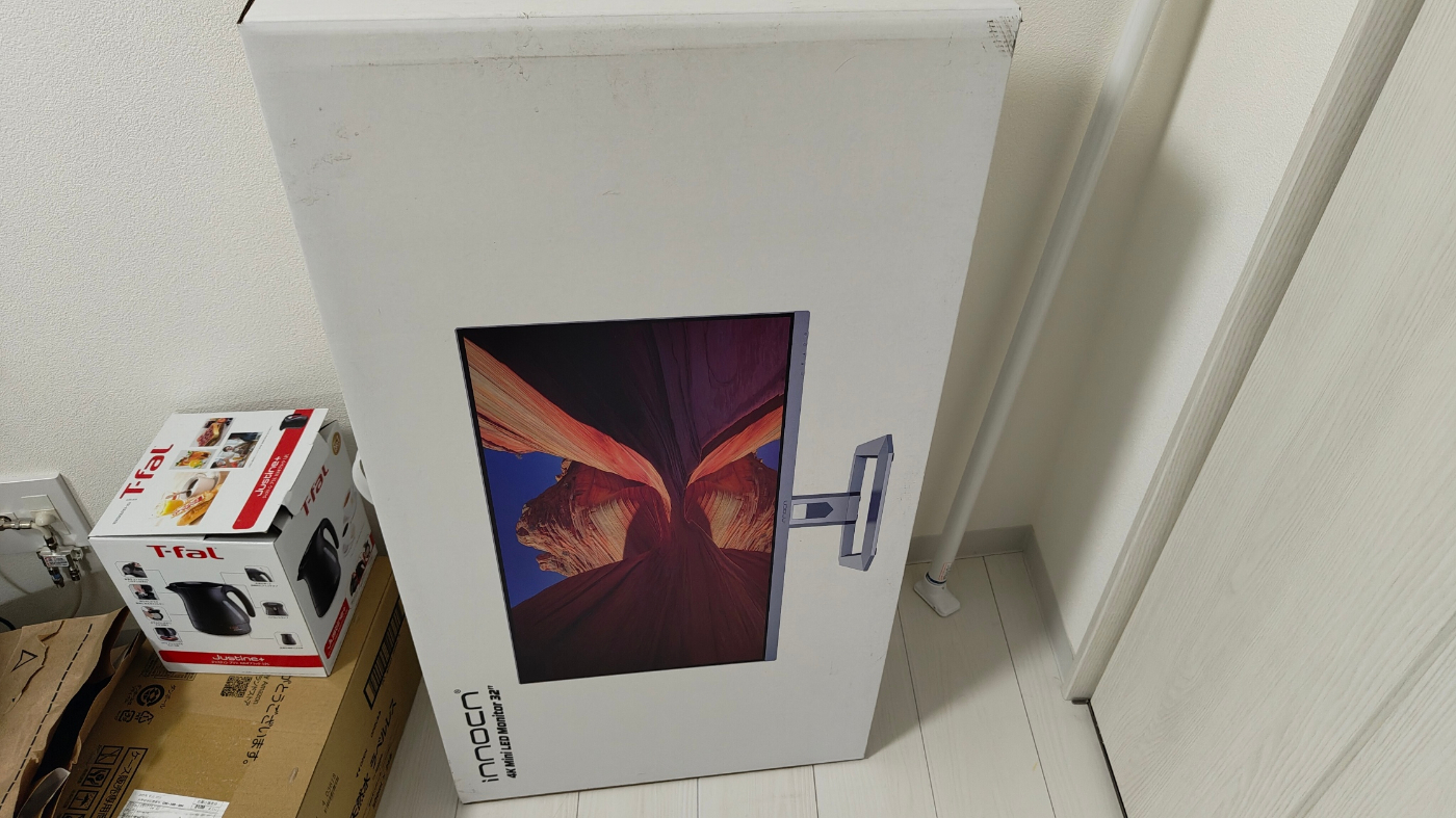 モニターの外箱を撮影した写真、普通の段ボールと比較しても大きいサイズであることが伺える。