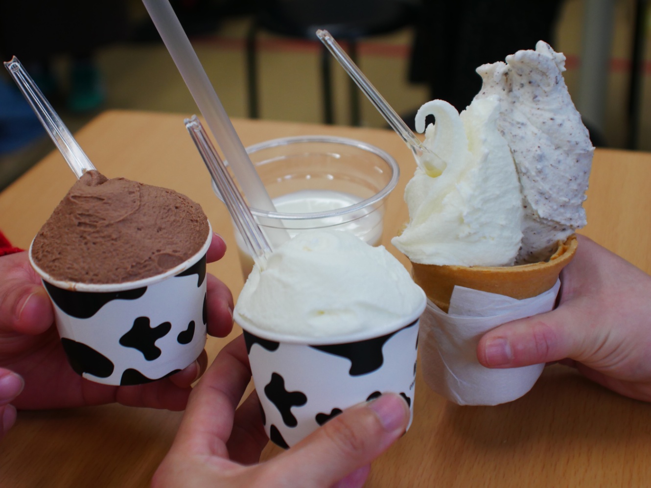 3人の人物の手元の写真。ジェラートの入ったカップやコーンを寄せ合っている。