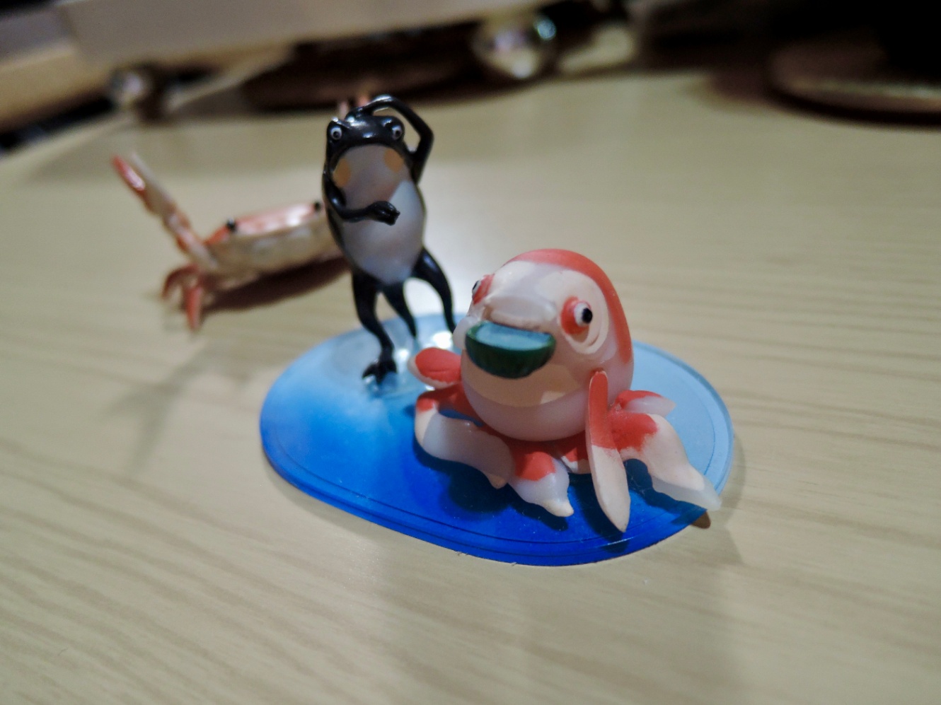 歌川国芳の金魚とカエルの絵をモチーフにしたフィギュアの写真。うしろには蟹の置物。
