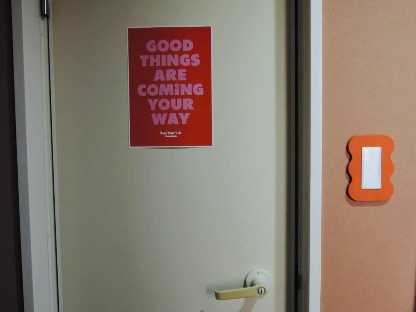 トイレのドアの写真。"GOOD THINGS ARE COMING YOUR WAY"と書いてあるポスターが貼ってある。