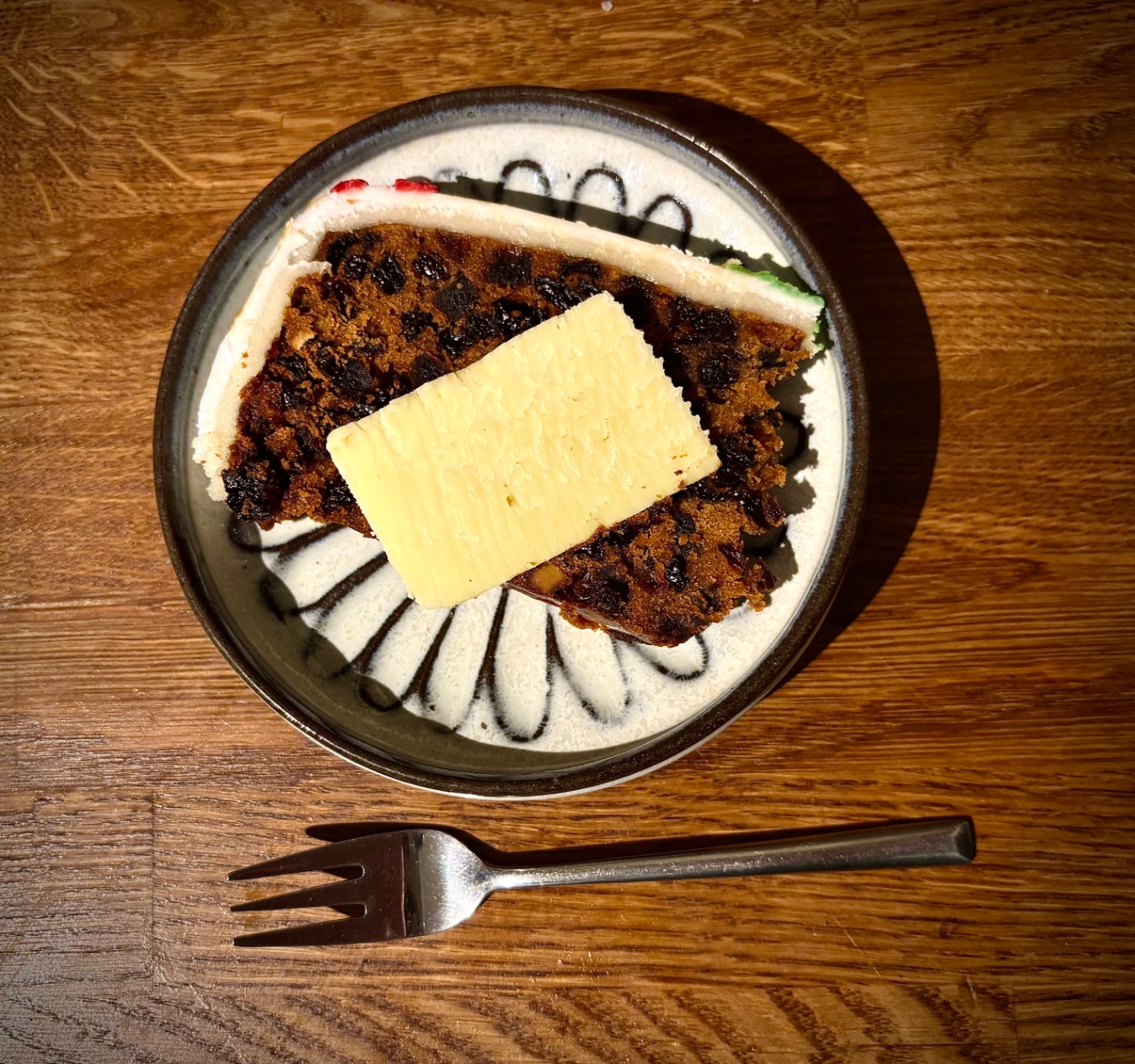 クリスマスケーキのスライス。たっぷりドライフルーツが入っている。その上にチーズのスライスも。