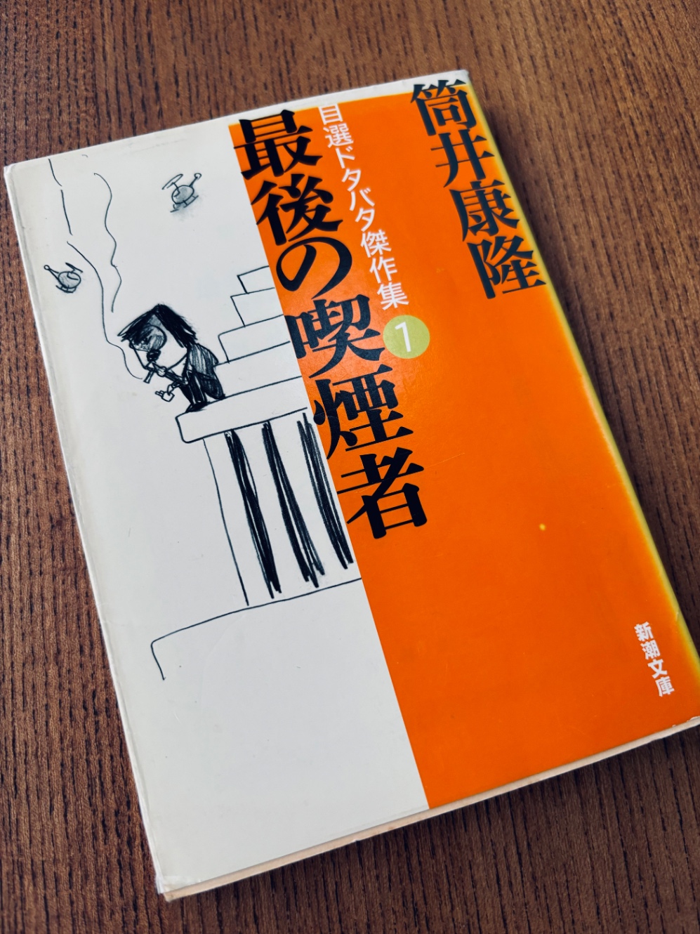 筒井康隆、自選ドタバタ短編集『最後の喫煙者』表紙。筒井氏に似た男がビルの屋上でタバコをふかしているイラスト。空にはパトロールのヘリコプターが。