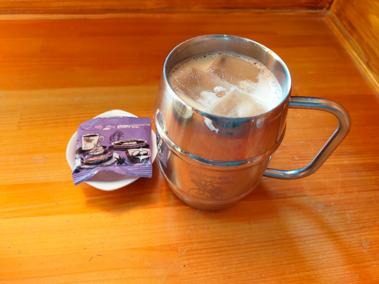 コメダ珈琲店で撮影した写真。たっぷりミルクコーヒーのアイスと、豆菓子が並んで写っている。豆菓子のパッケージは淡めの紫色をしている。