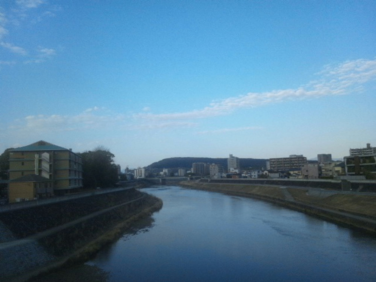 熊本市近郊の明午橋(明吾橋)から撮った青空と白川(しらかわ)沿いの街の景色