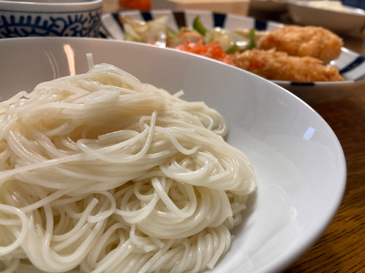 そうめんの入った器。奥に海老カツと焼き野菜の入った皿。