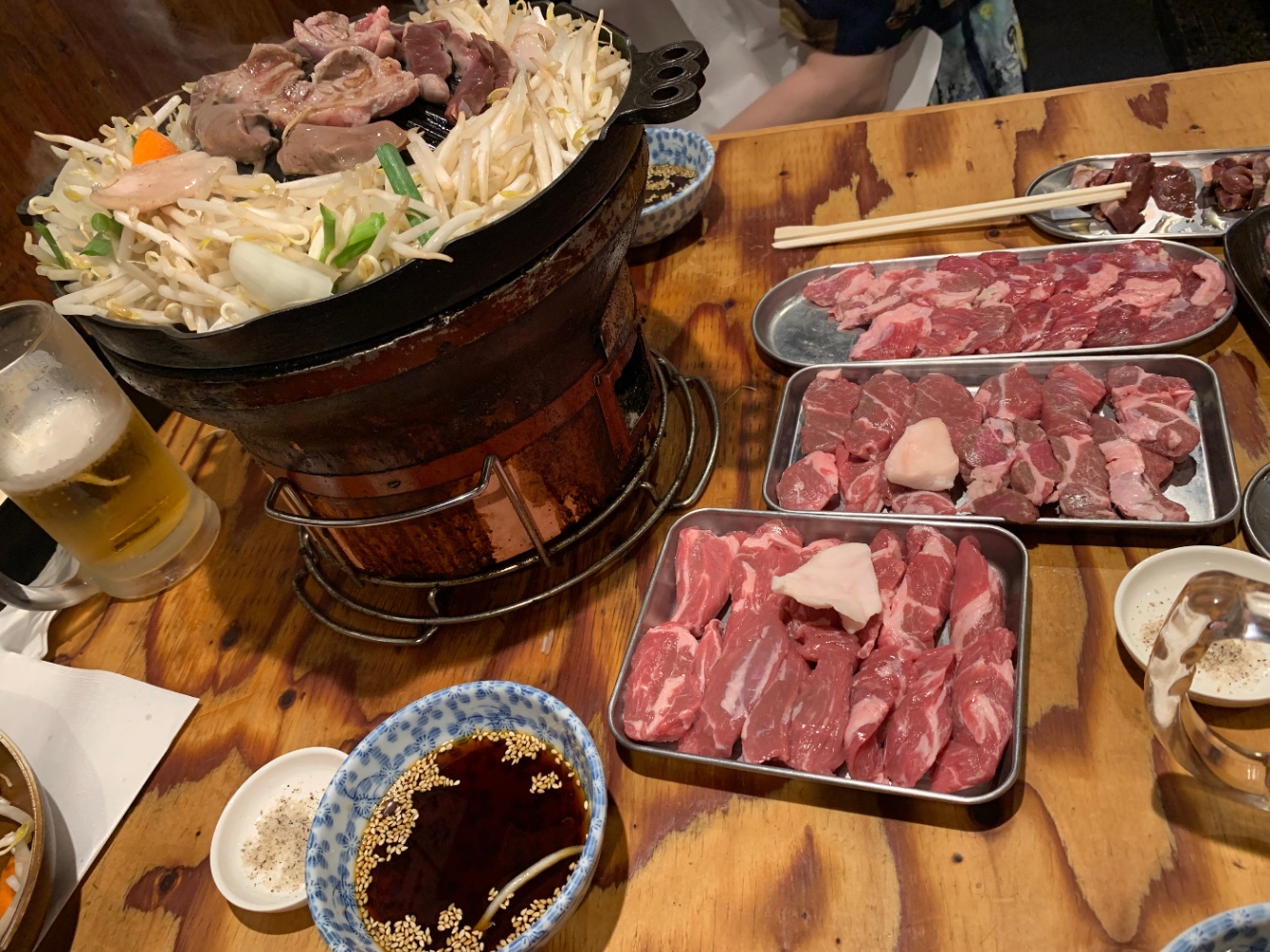 ジンギスカン鍋と、焼く前の生の羊肉が皿の上に盛られている写真