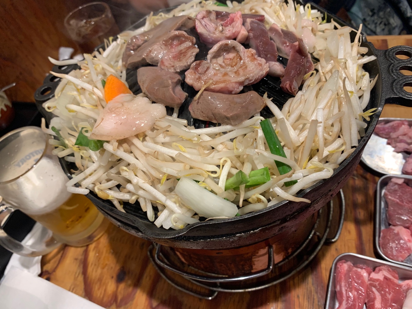 周りにもやしや野菜が乗っていて、真ん中に羊肉が焼かれているジンギスカンの様子。