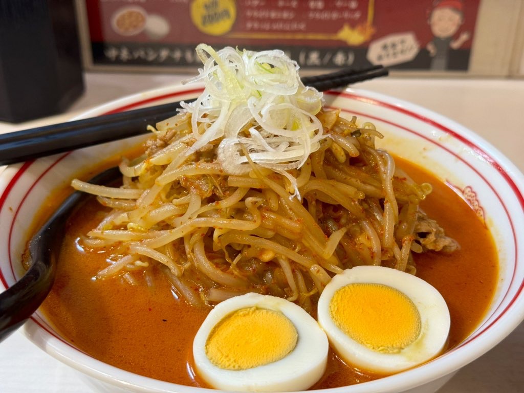 ラーメン鉢に満たされたオレンジ〜赤色のスープ、ゆで卵、もやし、刻み葱 (蒙古タンメン中本の味噌卵麺)