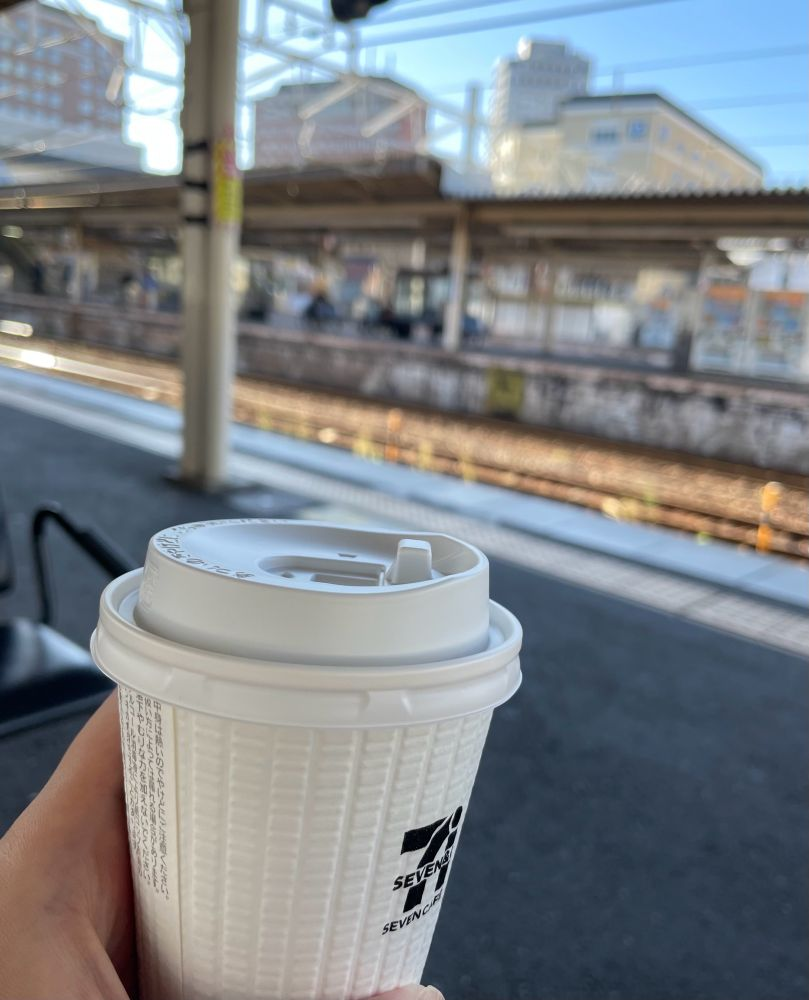 駅のホームと、ホットコーヒーの入った白いプラスチックカップ