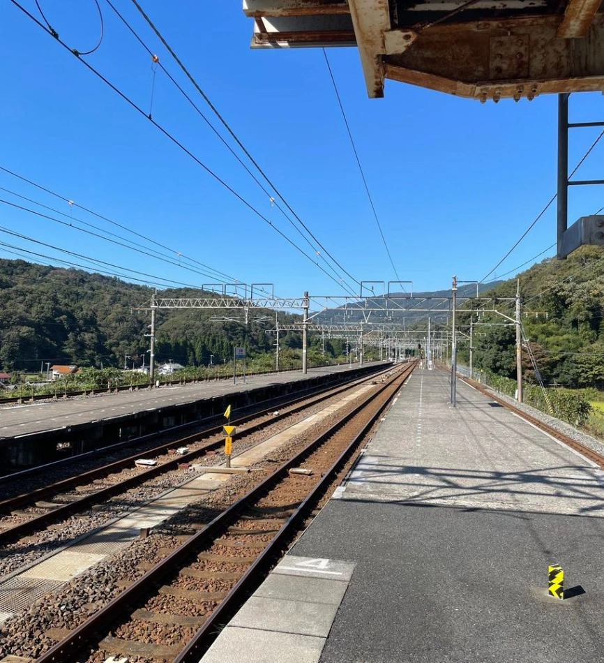 山間へ向かって伸びる鉄道の線路とホーム。青空が広がっている。