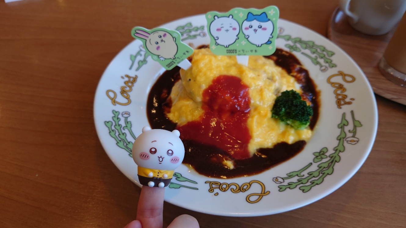 ちいかわコラボのデミハンバーグオムライス。ちいかわ、ハチワレ、うさぎつき。 手前の撮影者の指に特典のちいかわのソフビ人形が刺さっている