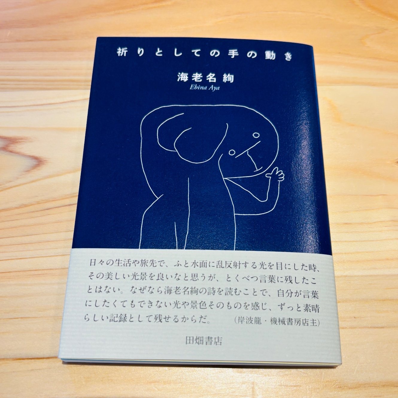 『祈りとしての手の動き』書影。濃紺に白抜き文字、白い線画(クレーの天使)