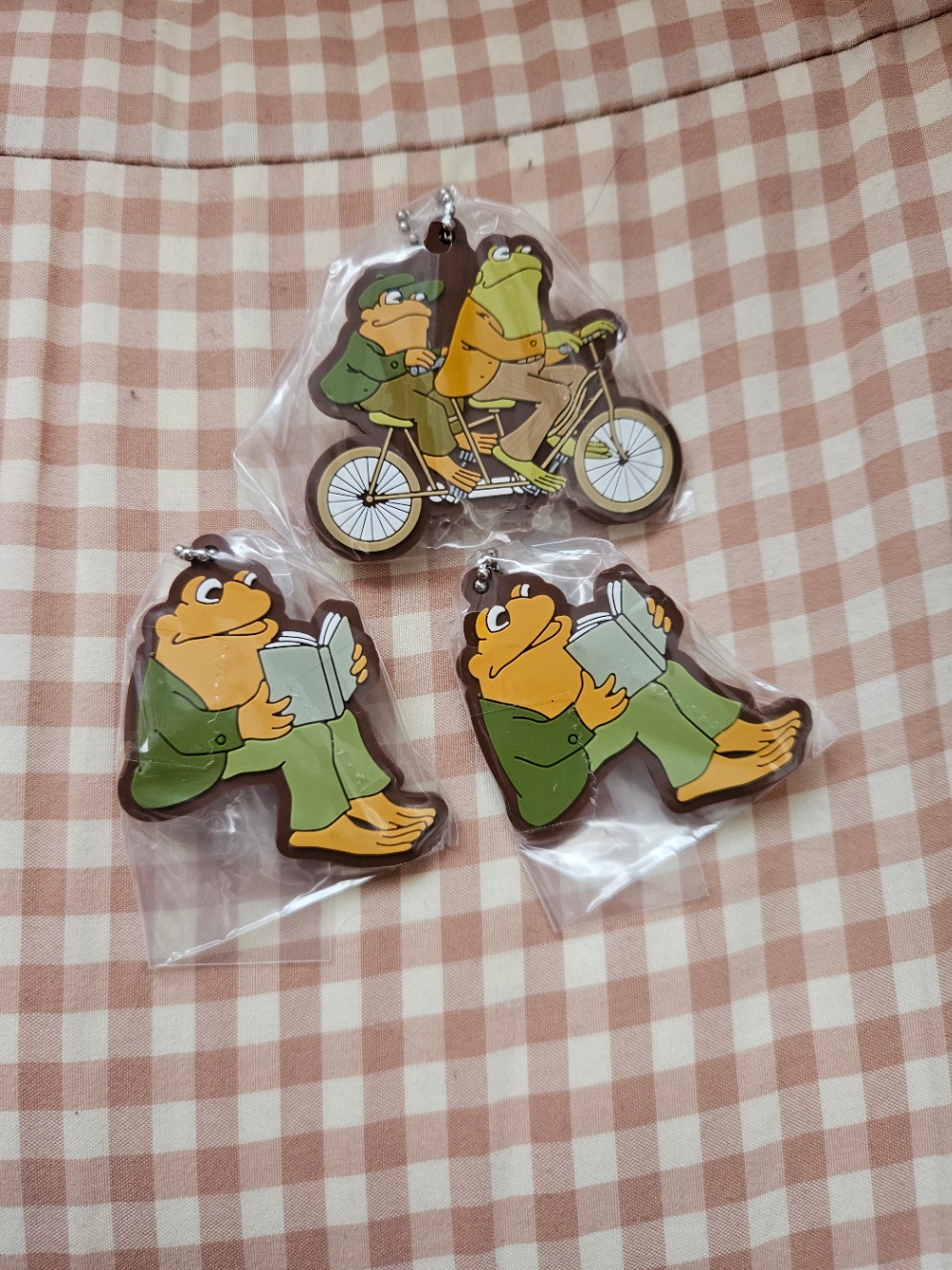 絵本「がまくんとかえるくん」シリーズのラバーマスコットの写真。がまくんとかえるくんが自転車を二人乗りしている柄が1つと、黄色いカエルが本を読んでいる柄が2つ。