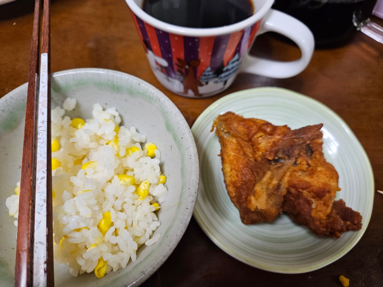 朝ご飯の写真。薄緑のお茶碗によそわれたとうもろこしご飯と、小皿に乗ったフライドチキン、ムーミン柄のマグカップに注がれたコーヒー。