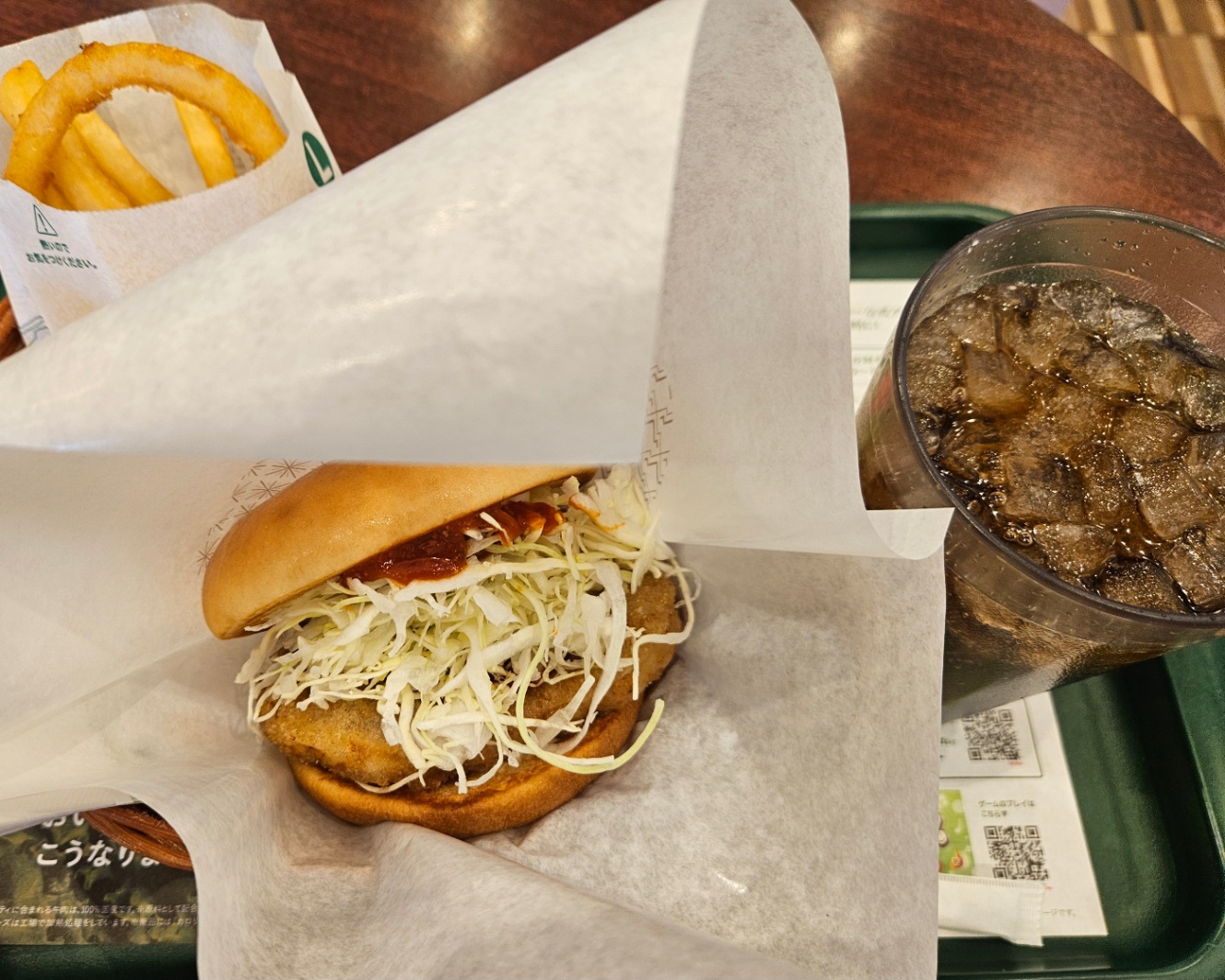 モスバーガーのガーリックトマトのとり竜田バーガーセットの写真。緑のトレーの上に、バーガー、ポテトとオニオンリングの袋、コーラが乗っている。