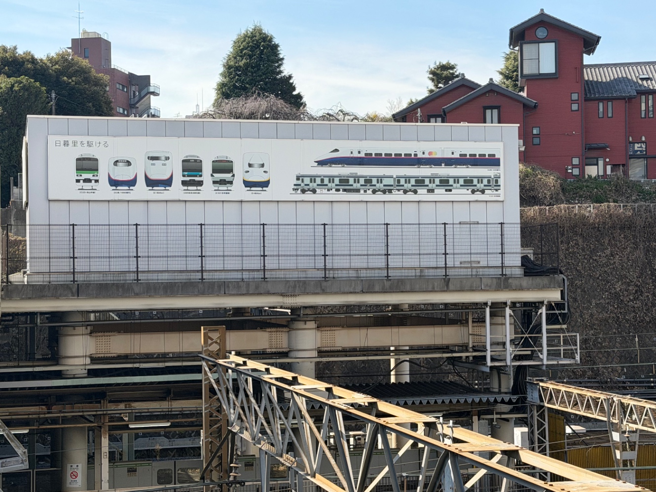 「日暮里を駆ける」という看板に、日暮里駅を通るJR線の車両が描かれている