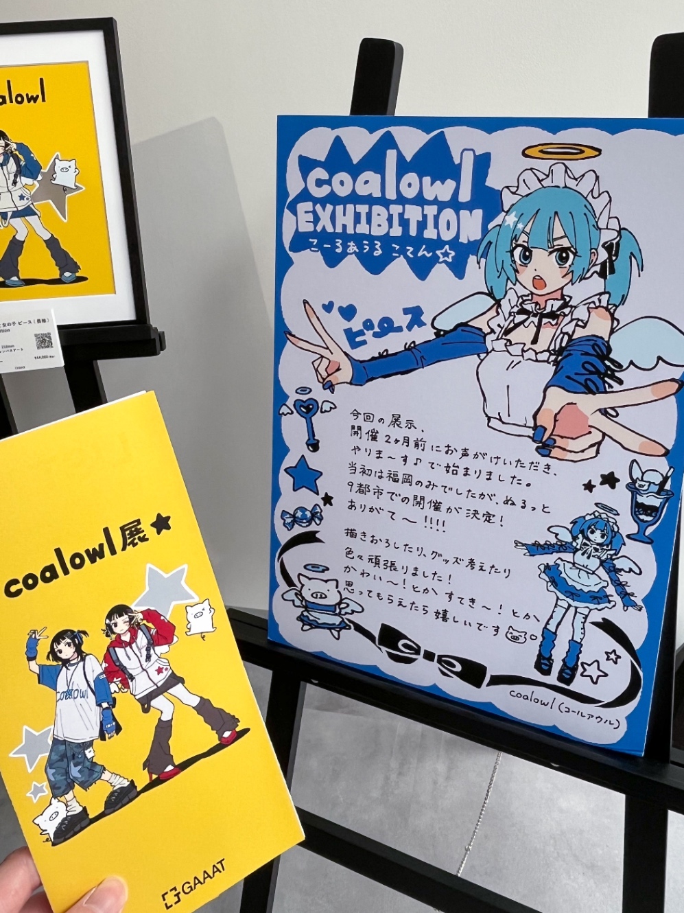 コールアウルさんの個展の入口。パネルに水色の髪の天使が両手でピースをしている。ご本人からのコメントもある。「今回の展示、開催2ヶ月前にお声がけいただき、やりま〜す♪で始まりました。当初は福岡のみでしたが、ぬるっと9都市での開催が決定!ありがて〜!!!!描きおろしたりグッズ考えたり色々頑張りました!かわい〜!とかすてき〜!とか思ってもらえたら嬉しいです!」