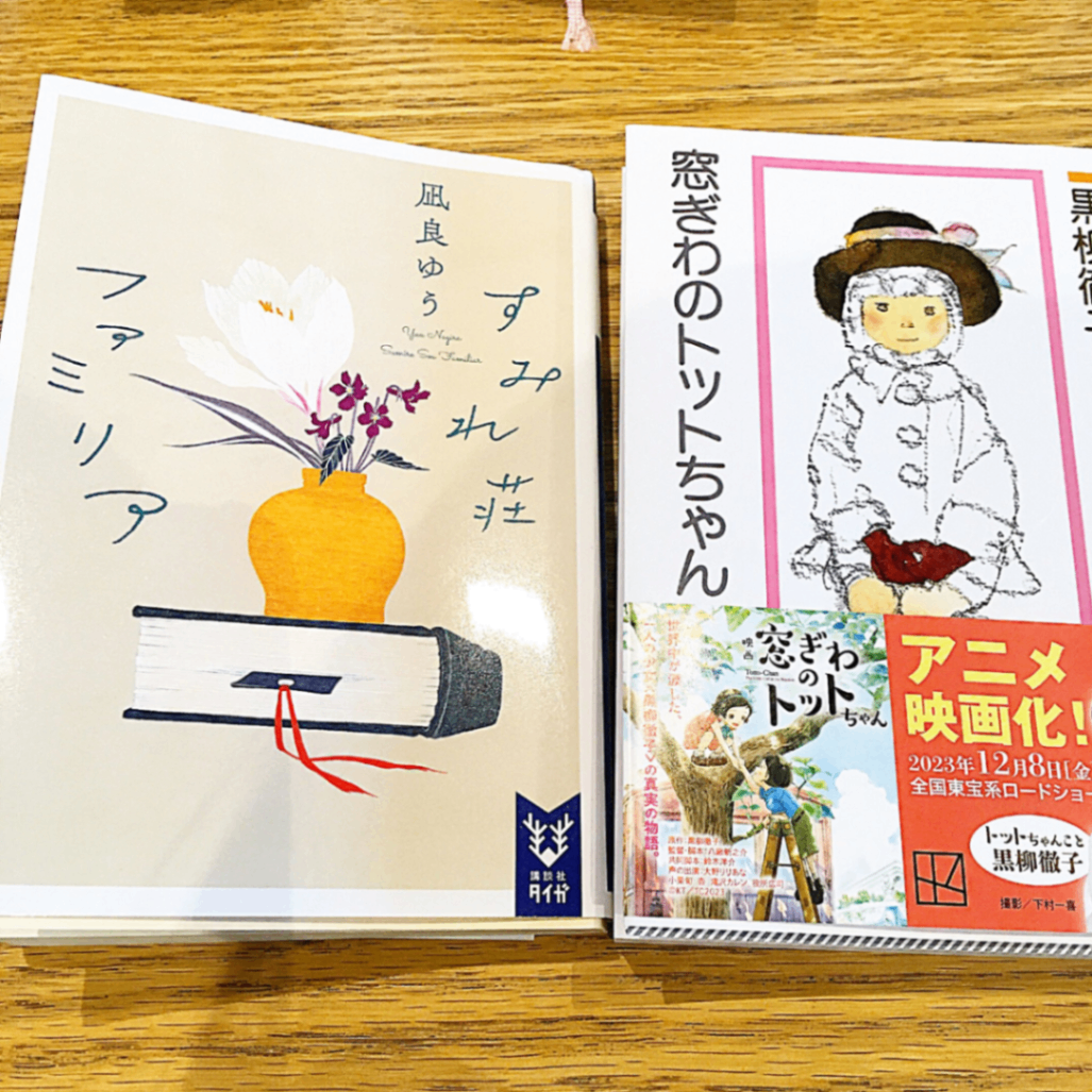 テーブルの上に2冊の本が並んでいる。凪良ゆう作「すみれ荘ファミリア」、黒柳徹子作「窓ぎわのトットちゃん」